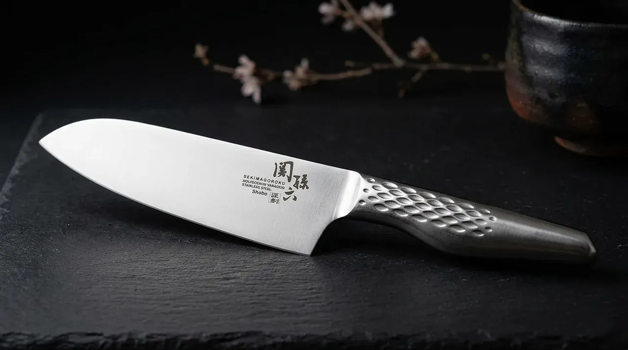 Cuchillo KAI Seki Magoroku Shoso Santoku 16,5 cm acero 5Cr15MoV mango de acero martillado sobre superficie de pizarra oscura
