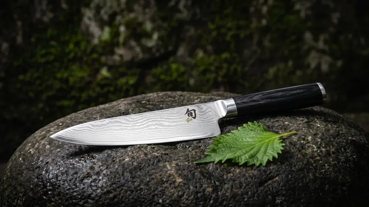 KAI Shun Classic Gyuto 20 cm con patrón damasco y logo Shun sobre piedra oscura con hoja de shiso