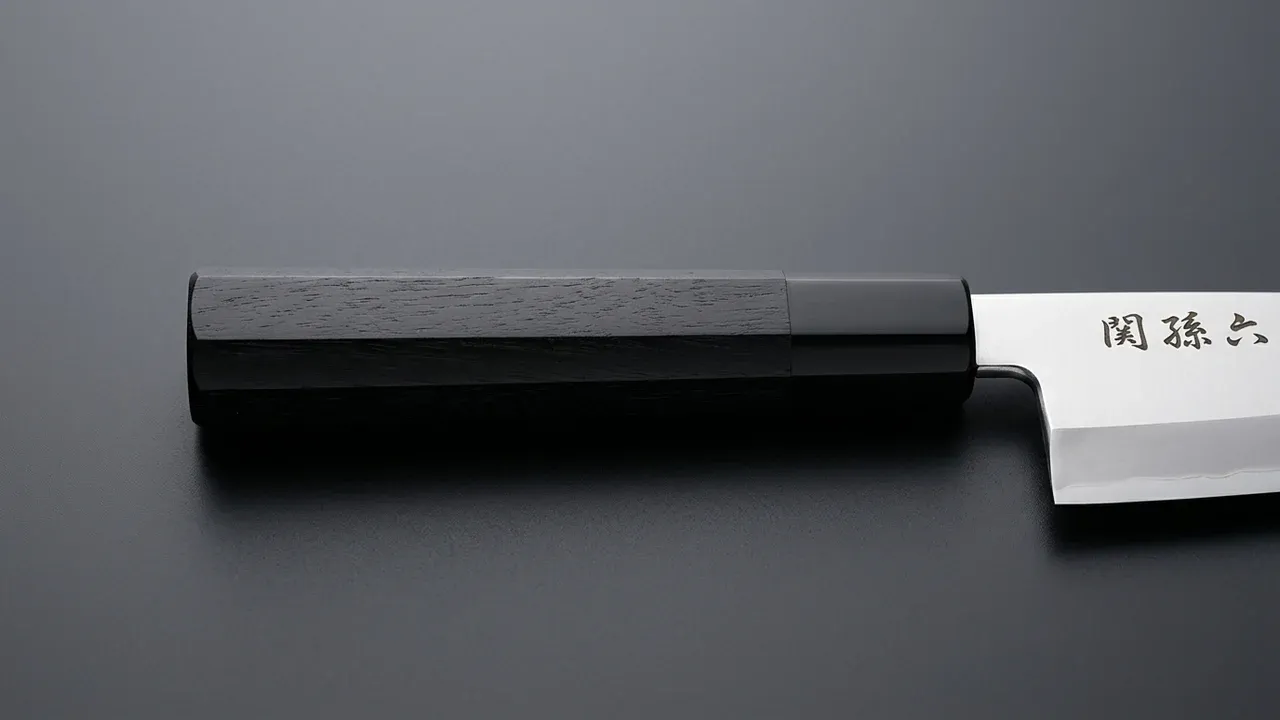 Detalle del mango octogonal de madera Pakka negra del cuchillo deba KAI Seki Magoroku de 180 mm, con sus facetas y el collar negro