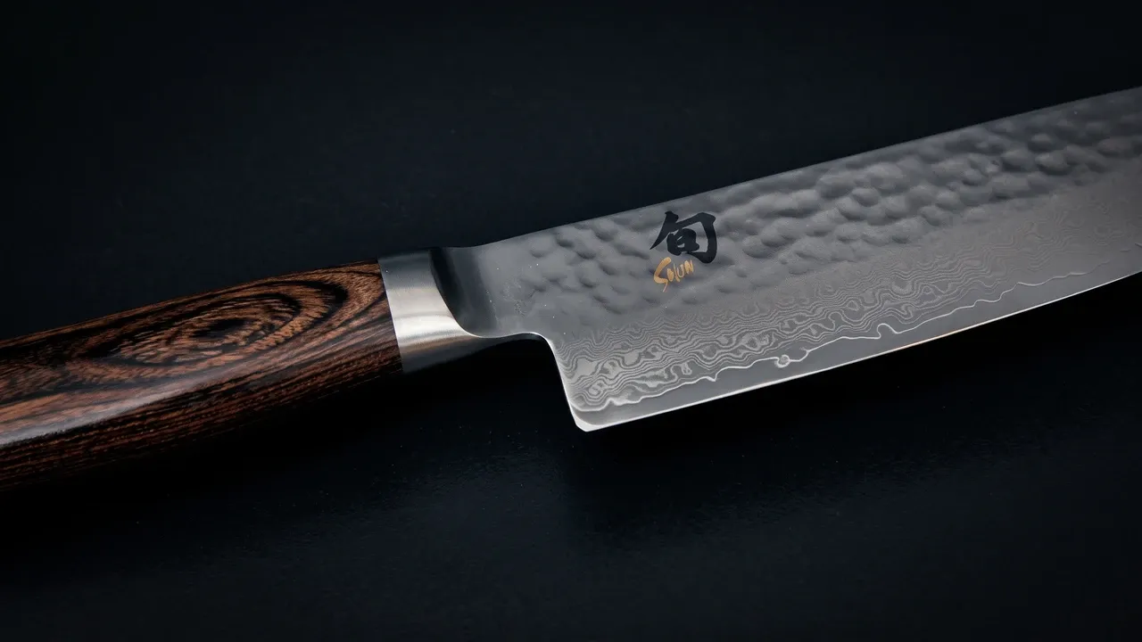 Hoja del KAI Shun Premier con el martillado tsuchime, el damasco de 32 capas y el kanji Shun grabado junto al mango de pakka marrón
